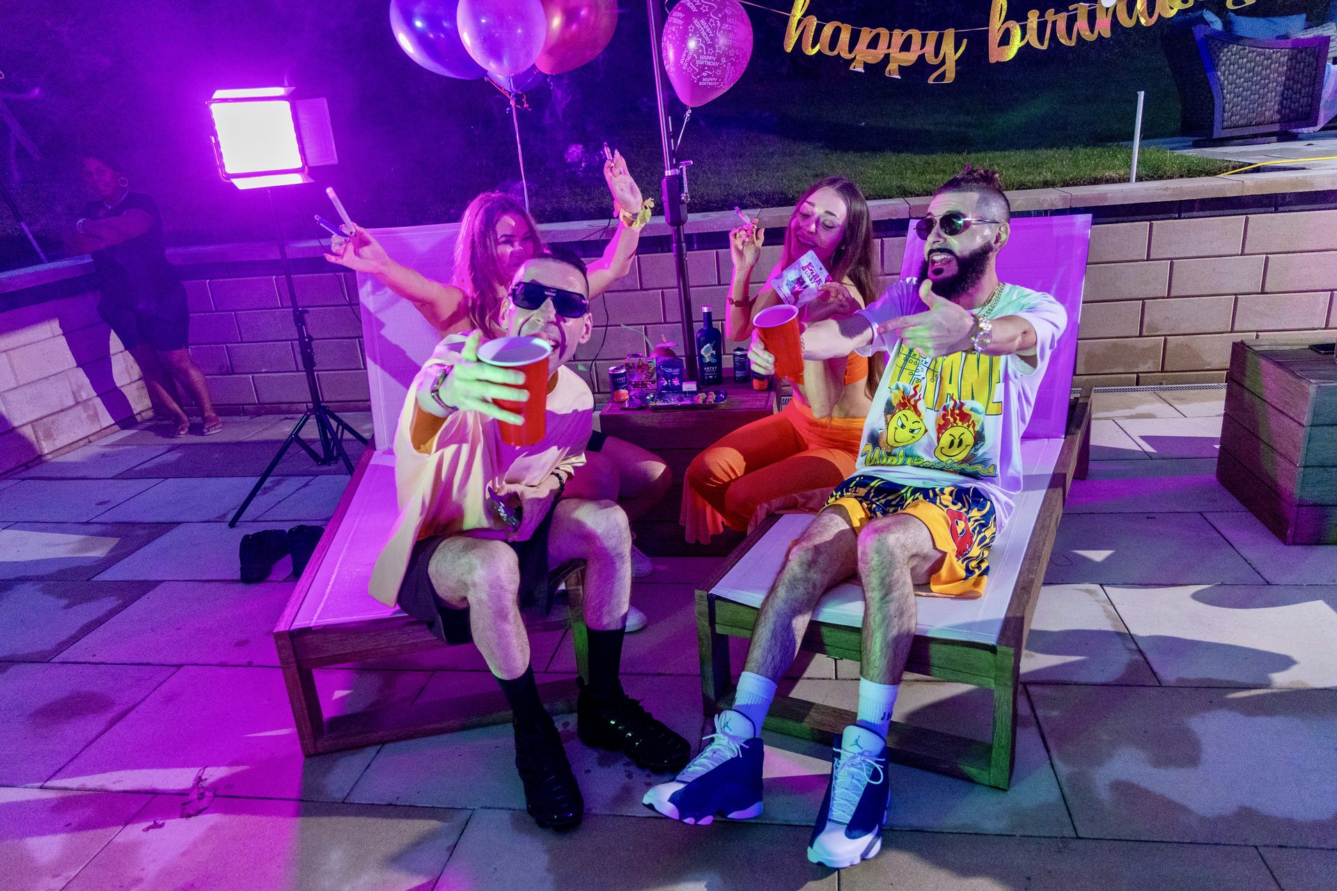 KING T and LUSS on loungers under magenta party lights