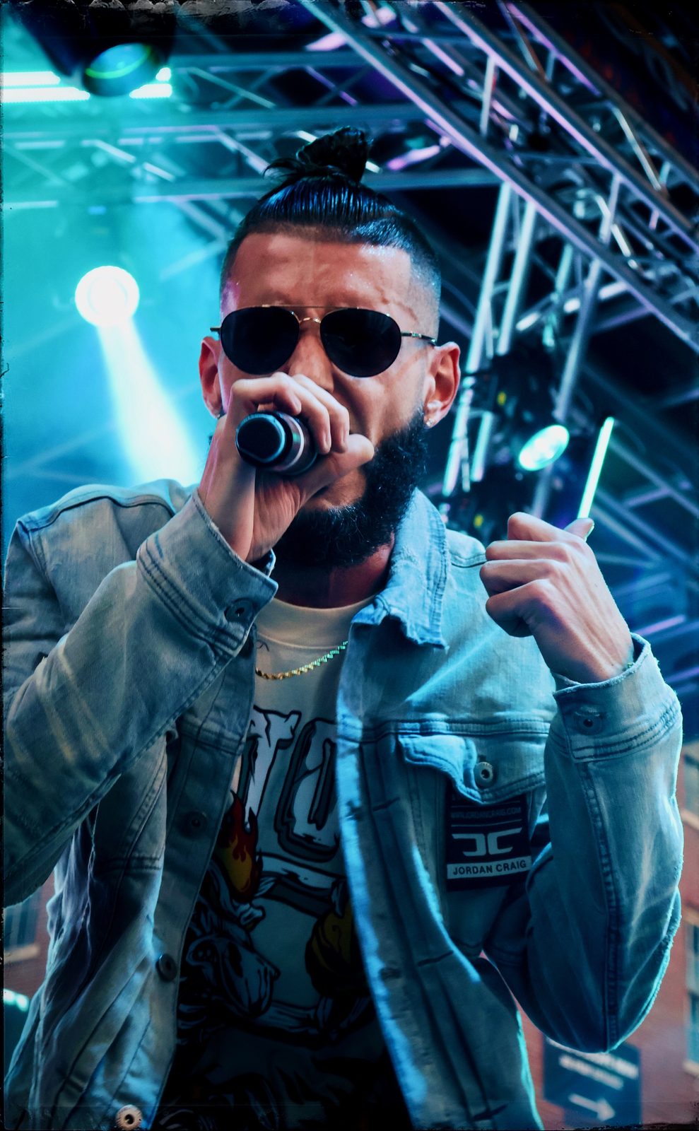 KING T performing with a mic on stage in a denim jacket
