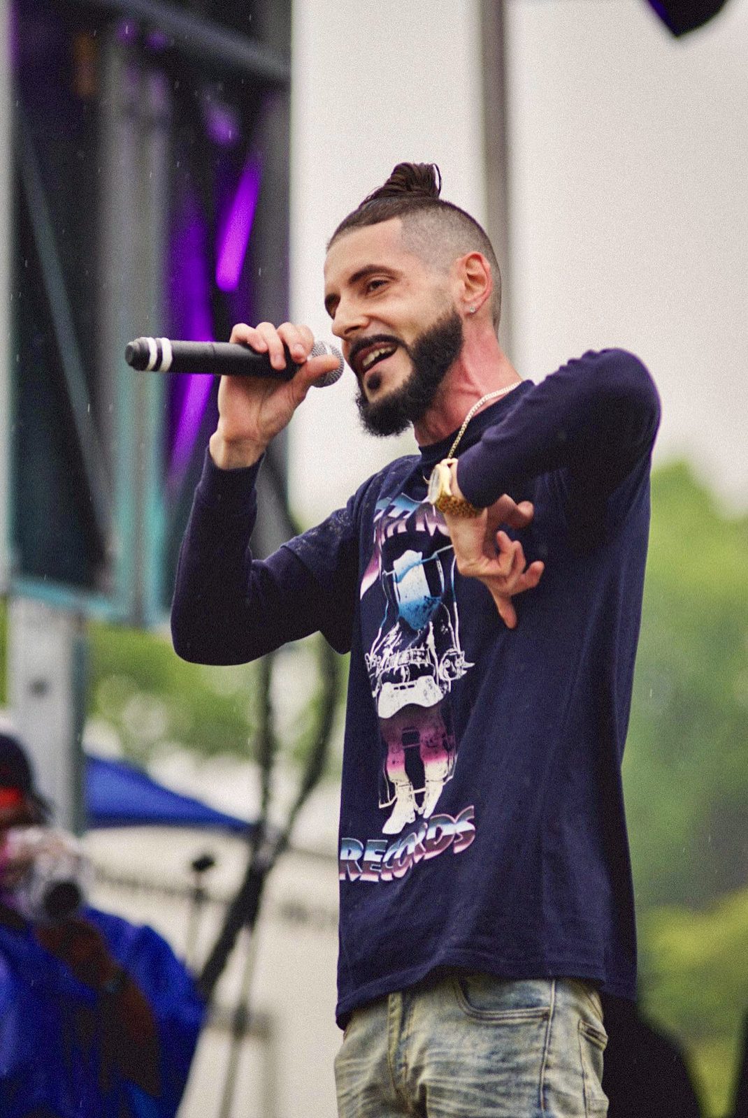 LUSS rapping into a microphone on an outdoor stage